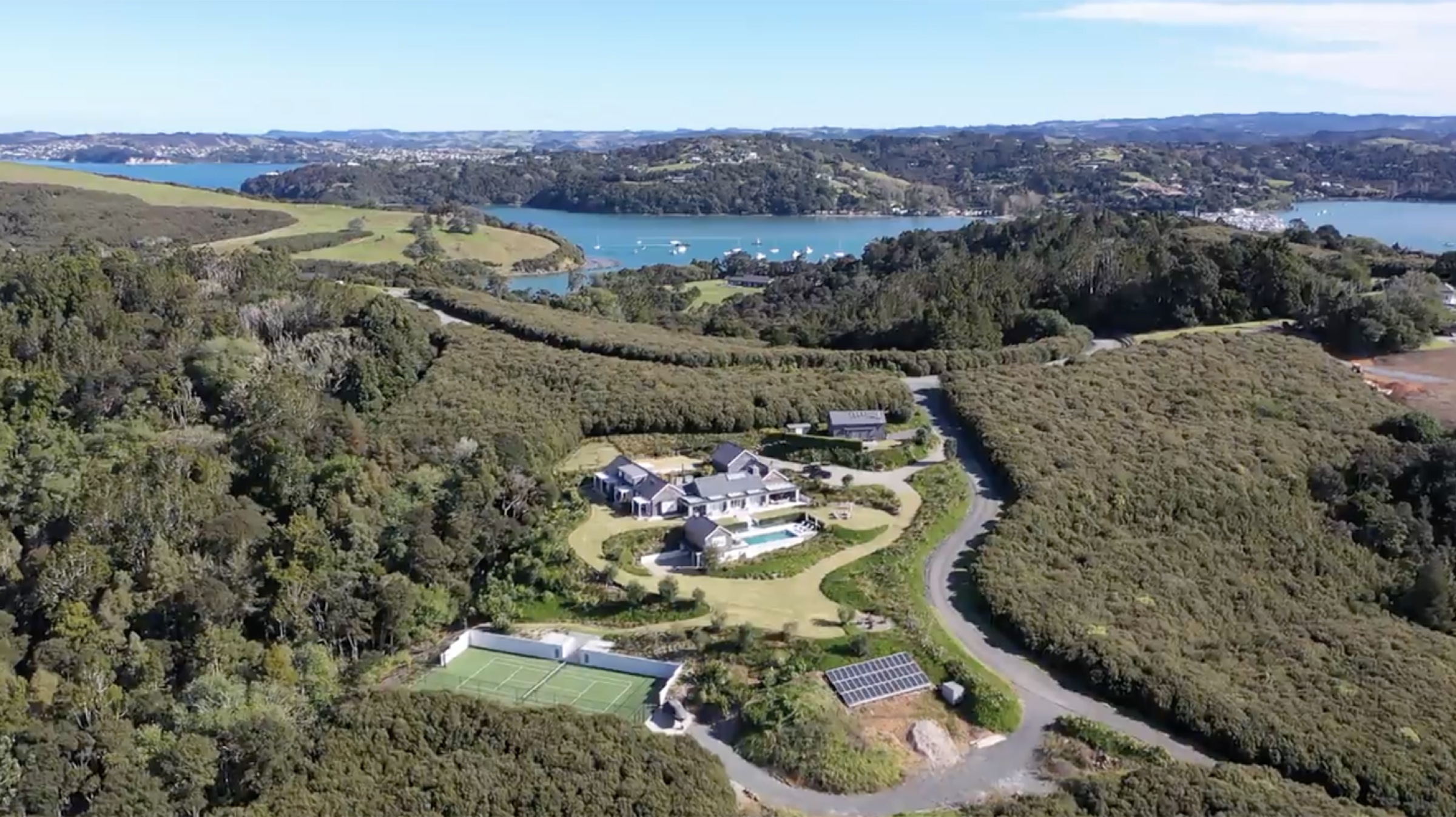 Bluestone Main Estate from the air: the Main House and pool, the Boat House, the tennis court and solar farm below, all held in native bush above the Matakana estuary and the boats at Sandspit.