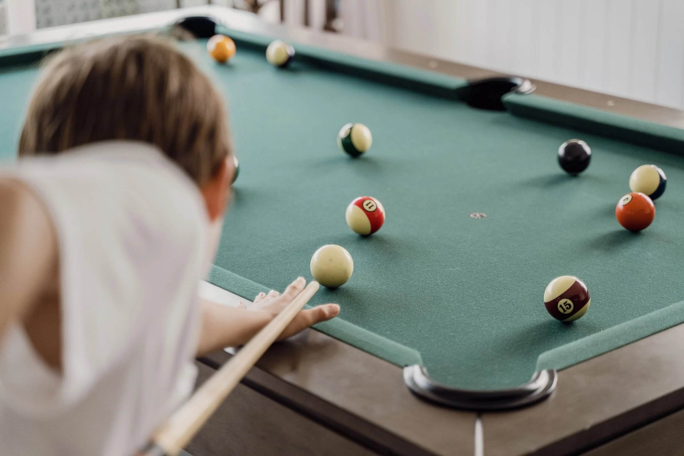 A child lining up a shot on the pool table in the pool house at Bluestone Main Estate.