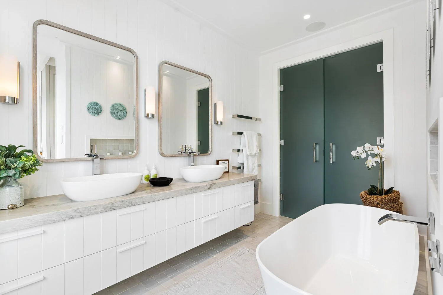 An ensuite in the Main House at Bluestone Estate with twin basins, a freestanding bath, and green glass doors.