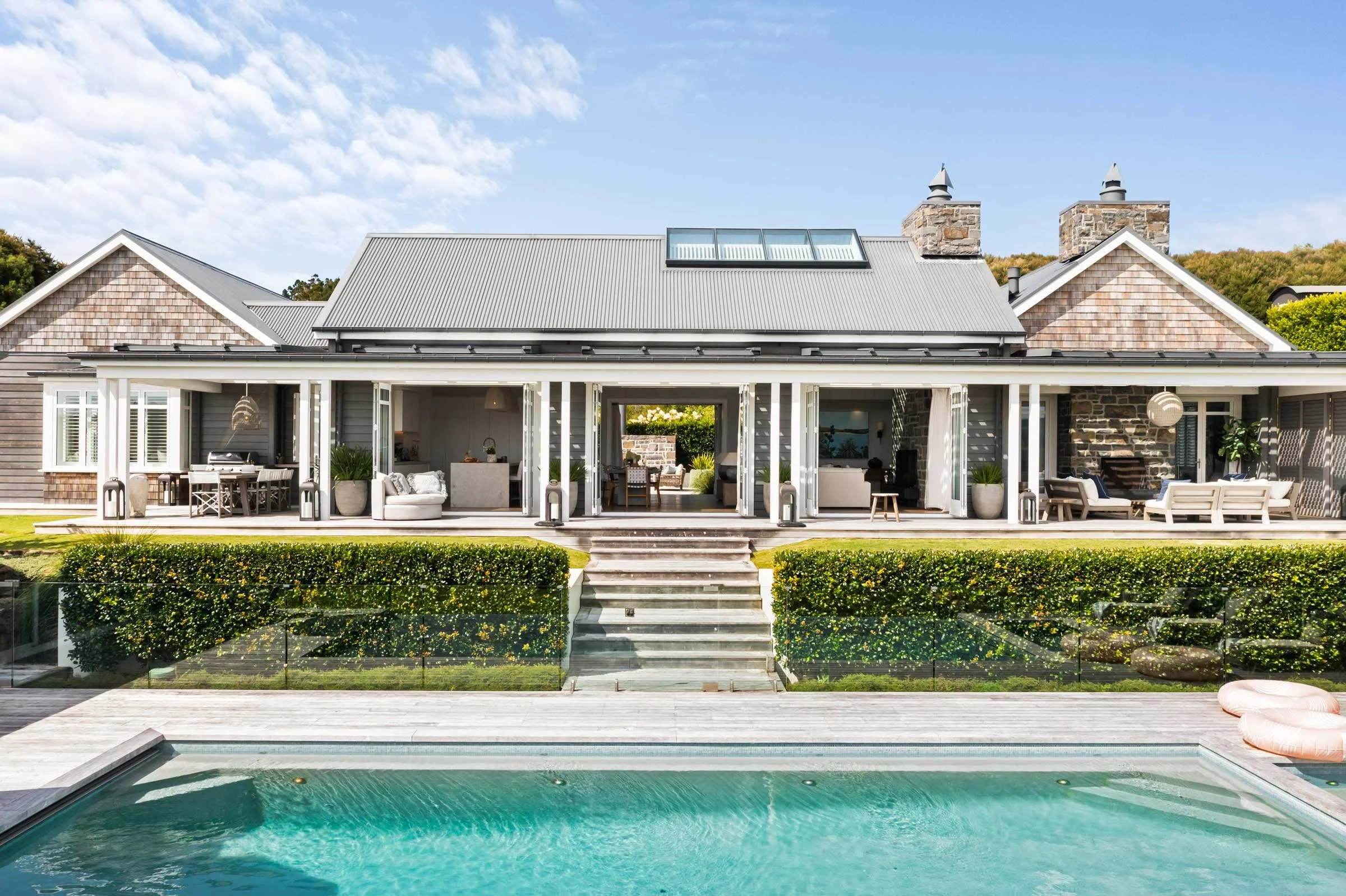 The Main House at Bluestone Estate seen across the infinity pool, with its two stone chimneys.