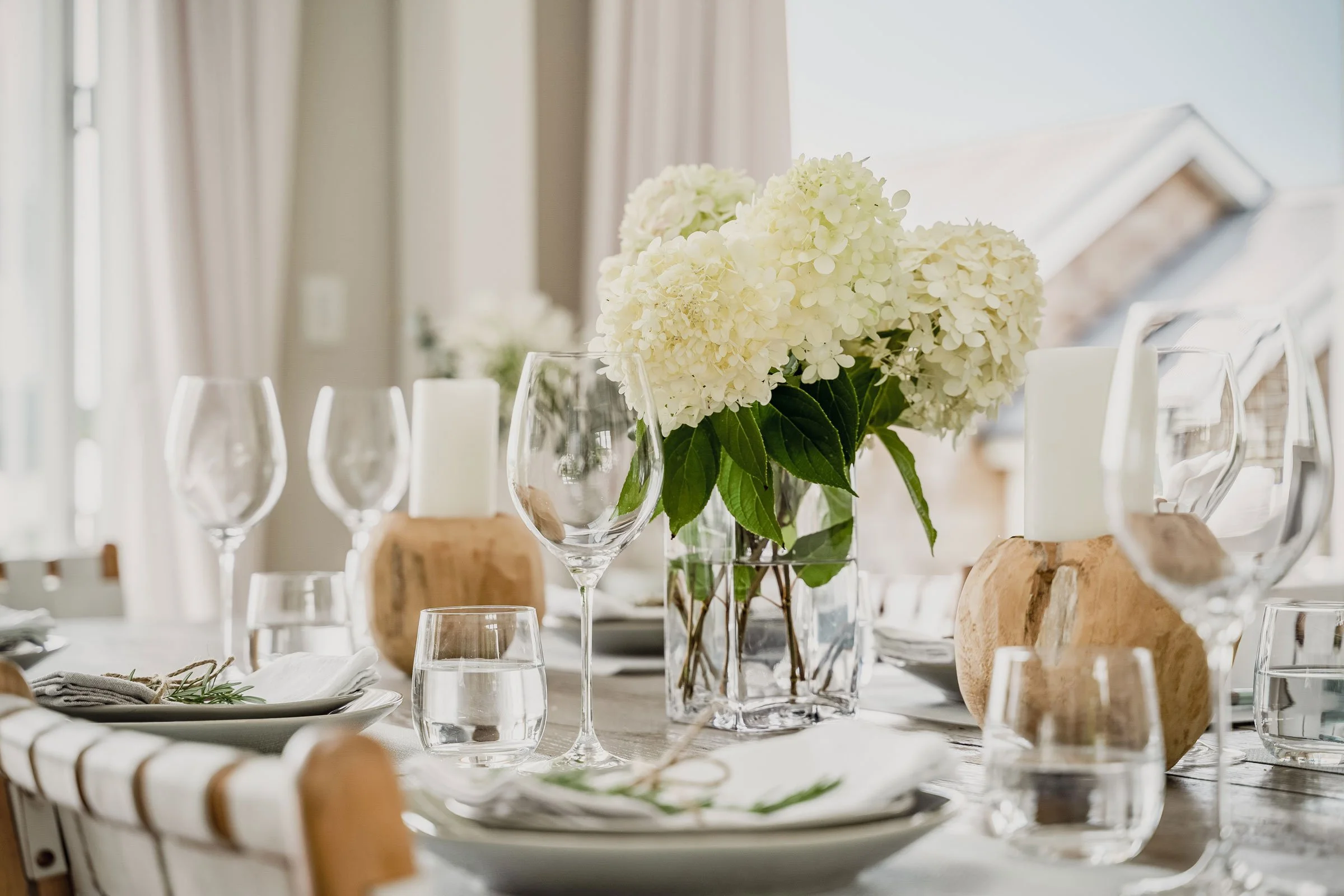 The Main House dining table at Bluestone Estate set with white hydrangeas, candles, and wine glasses.