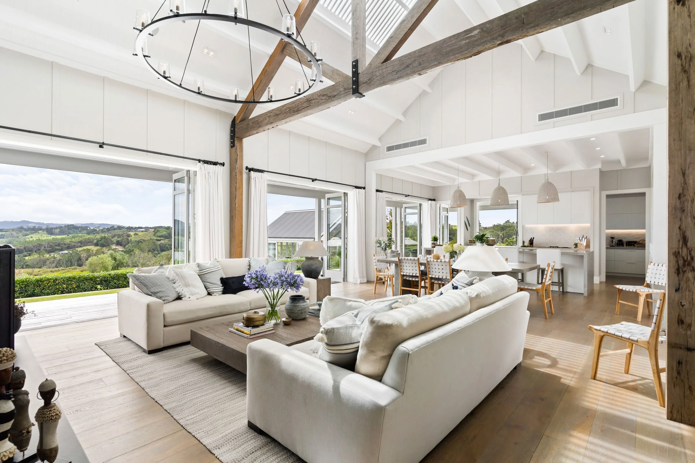 The vaulted living room of the Main House at Bluestone Estate, doors open to the view, with the kitchen beyond.
